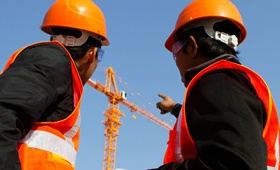 Two Construction Workers Pointing at a New Crane