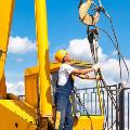 Worker attaching hoist and pulley parts to a mobile and rough terrain crane